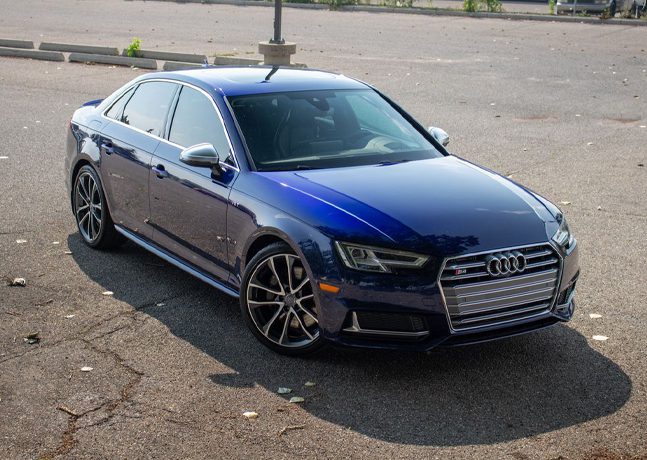 Blue Audi S4 sedan parked on asphalt, showcasing a glossy paint finish, highlighting the vehicle's sleek design and features relevant to paint correction services.
